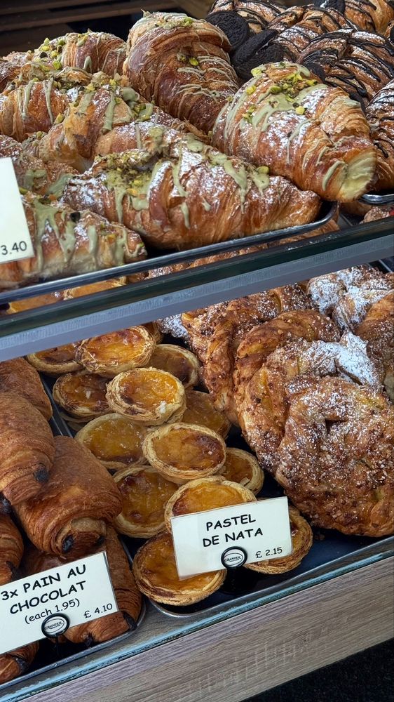 Cabinet shelves of pistachio croissants, pain au chocolat and pastel de nata