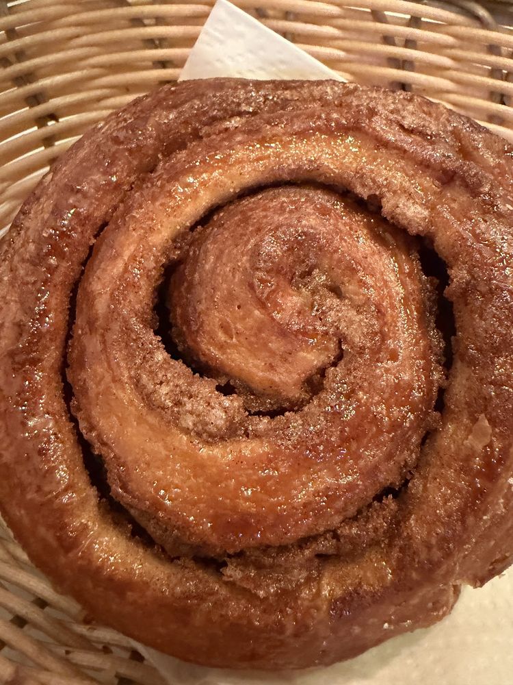 A large cinnamon swirl bun filling the frame in a basket
